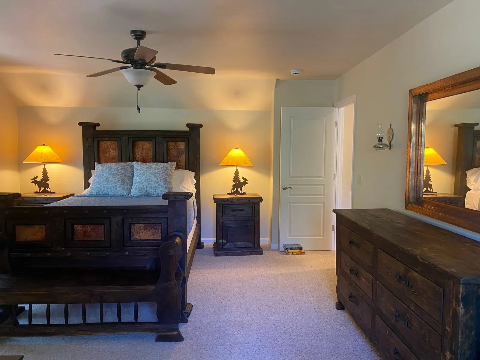 Bedroom with a dark wood bed, warm lamplight, and a dresser mirror