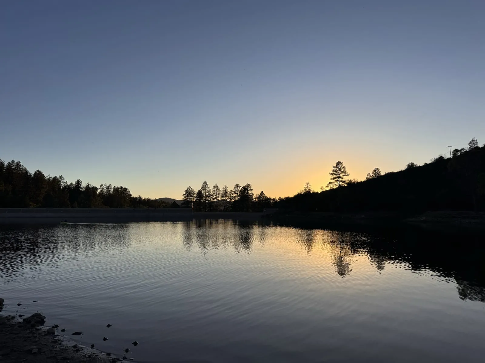 Sunset over a calm, pine-ringed lake near Prescott