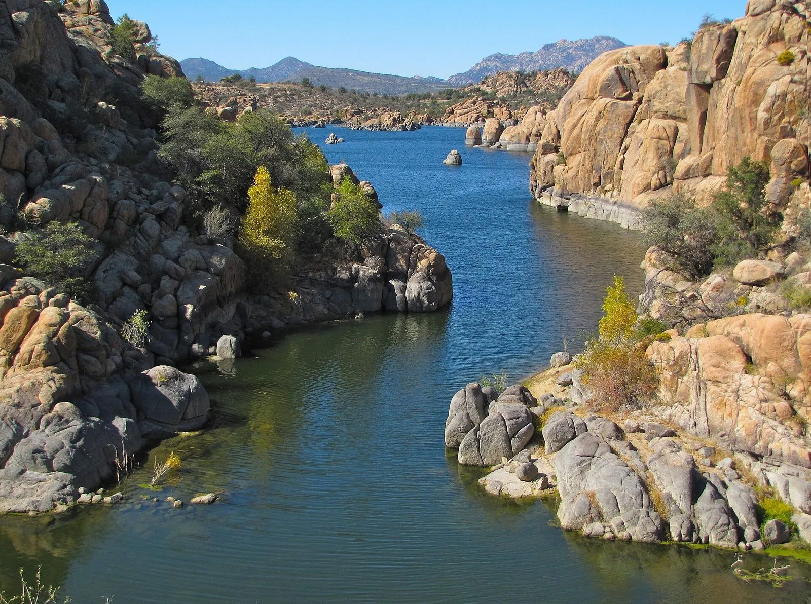 Blue water between granite boulders and low shrubs at Watson Lake near Prescott